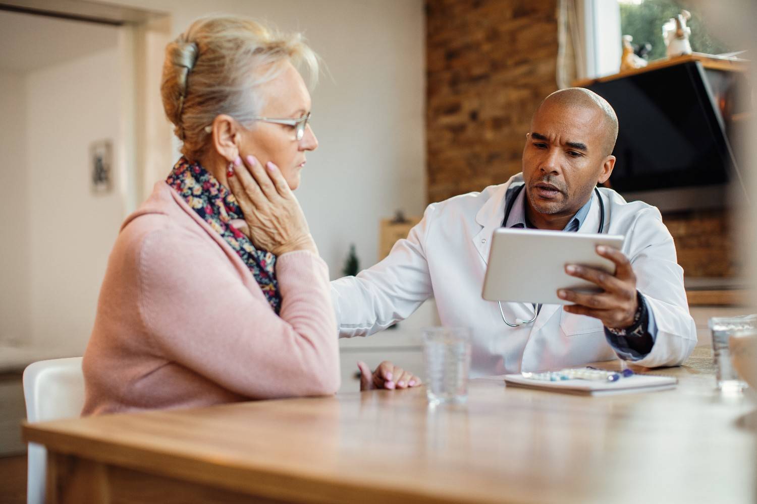 african-american-doctor-using-touchpad-while-talking-senior-woman-nursing-home2