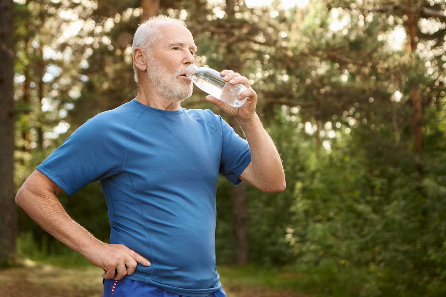 portrait-attractive-active-male-pensioner-with-bald-head-stubble-refreshing-himself-after-jogging-outdoors-standing-against-pine-forest-holding-bottle-drinking-water (1)